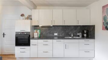 A modern kitchen with white cabinets, a built-in oven, and a coffee maker.