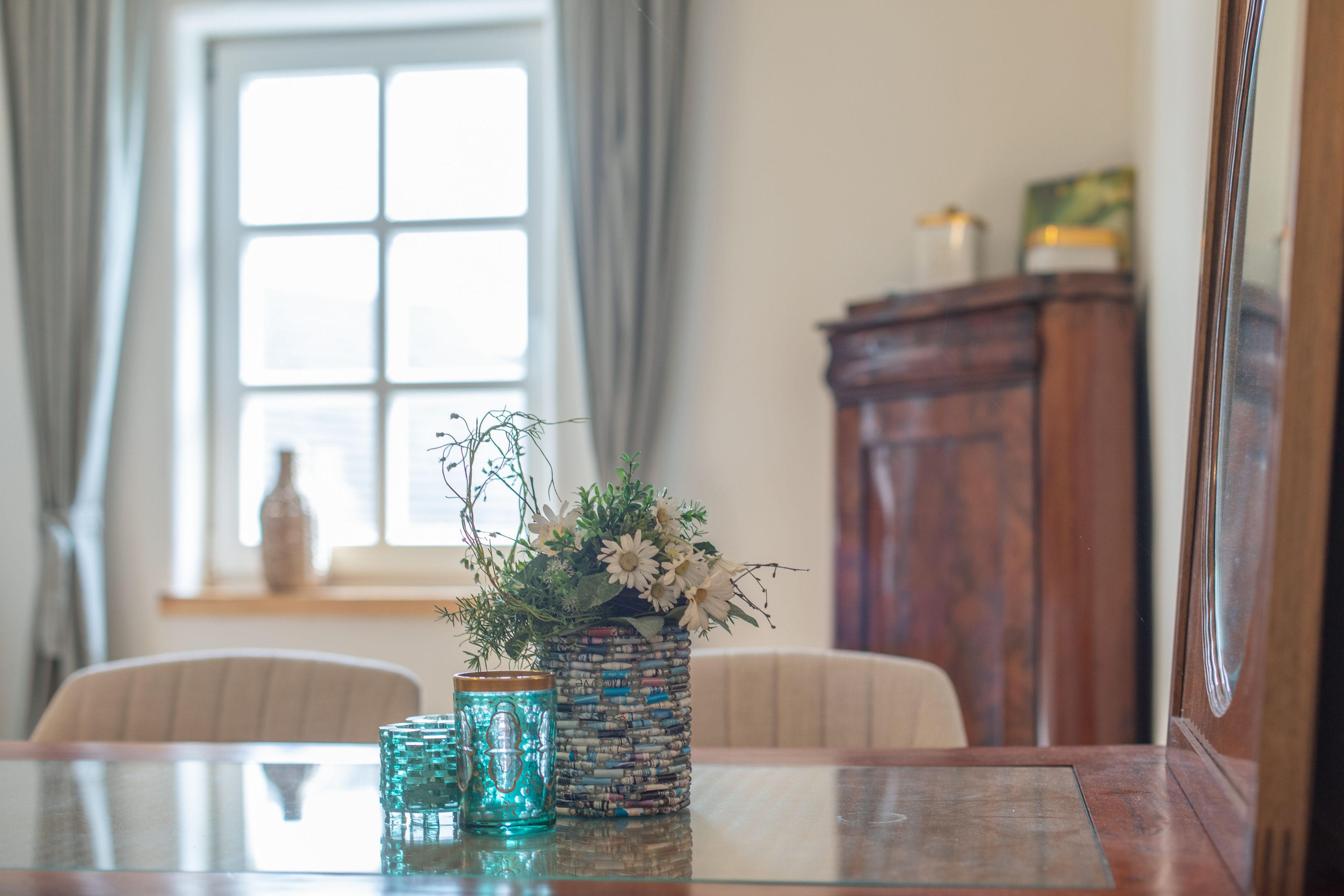 Ein Tisch mit Blumen in einer Vase und zwei Gläsern.
