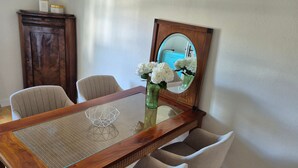 A dining table with a vase of flowers, chairs, a mirror, and a cabinet. - Denkmal Haus Hugo OG Apartment with Garden View and Wi-Fi (Medebach)
