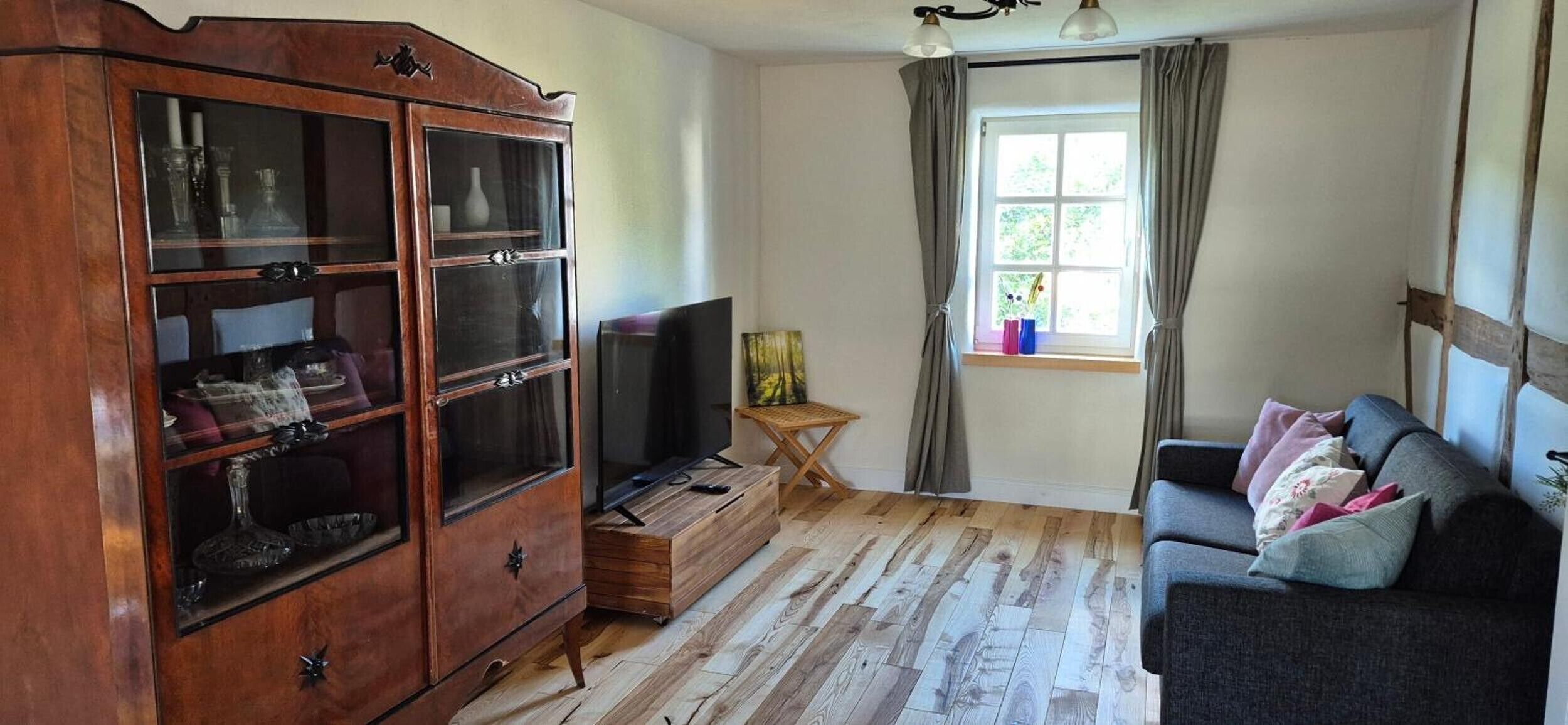 Ein Wohnzimmer mit Holzschrank, Fernseher, kleinem Tisch und einer Couch.