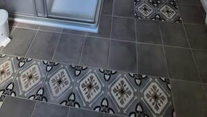 A shower enclosure with a glass door, a wooden bench, and patterned floor tiles. - Denkmal Haus Hugo OG Apartment with Garden View and Wi-Fi (Medebach)