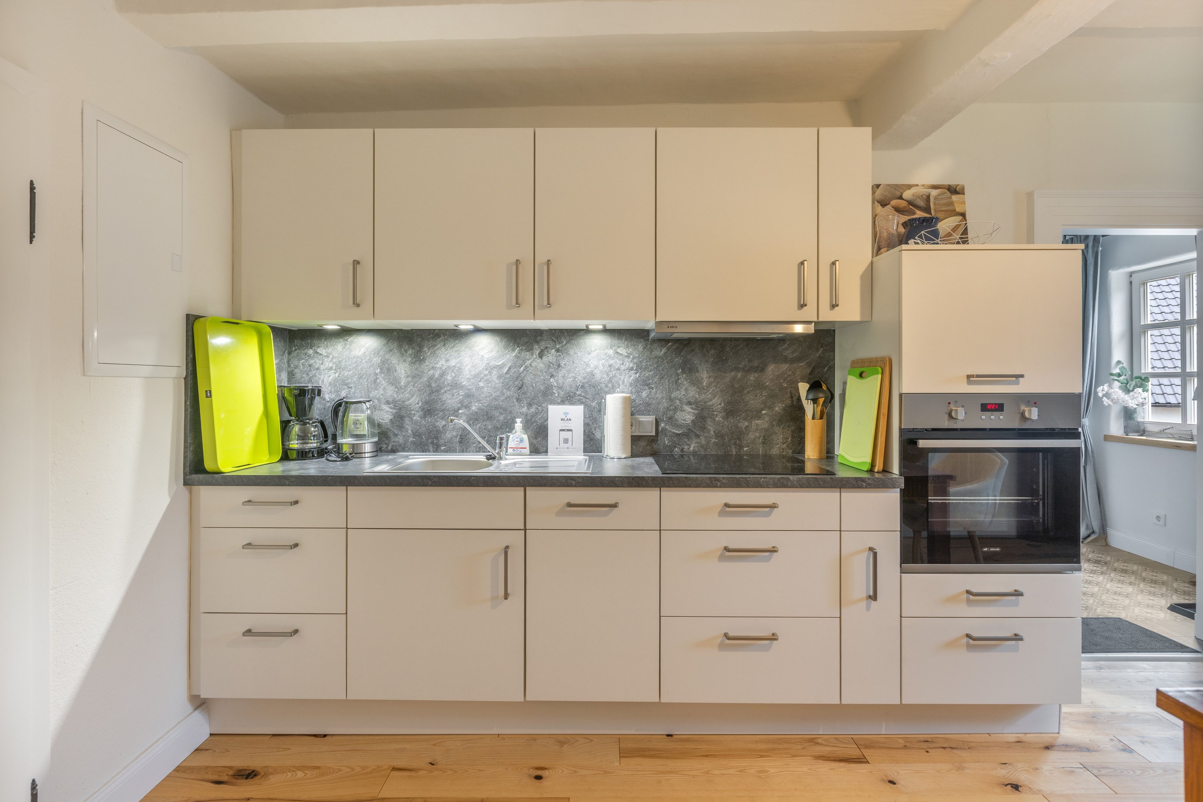Een moderne keuken met witte kasten, een ingebouwde oven en een magnetron.