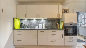 Een moderne keuken met witte kasten, een ingebouwde oven en een magnetron.