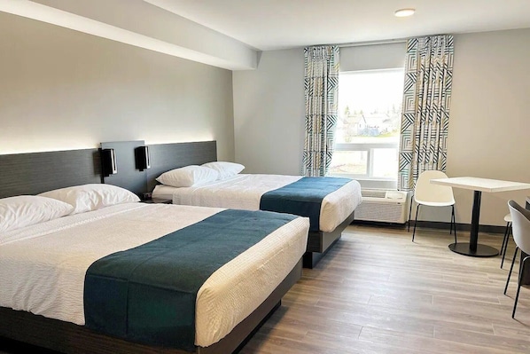 Een hotelkamer met twee bedden, een tafeltje, stoelen en een raam met gordijnen.