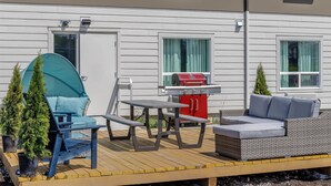 Une terrasse dotée de mobilier d’extérieur, d’un barbecue et de plantes en pot.