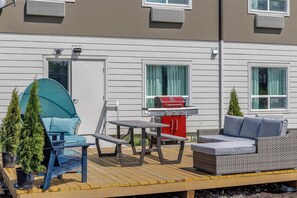 Een terras met buitenmeubilair, een barbecue en potplanten.