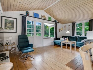 A cozy living room with a wooden ceiling, a blue sofa, a green armchair, and a small table. - "Söffren" - 450m to the fjord by Interhome (Øster Assels)