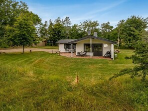 A single-story house with a patio area, surrounded by a well-maintained lawn and trees. - "Söffren" - 450m to the fjord by Interhome (Øster Assels)