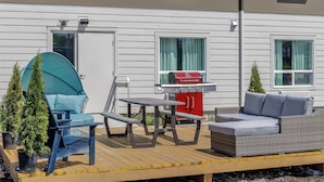 Une terrasse dotée de mobilier d’extérieur, d’un barbecue et de plantes en pot.