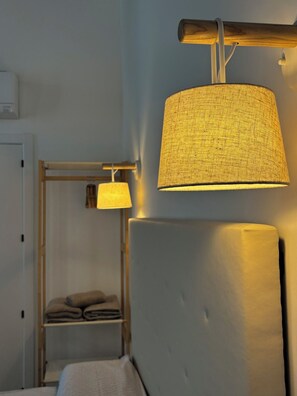 Une chambre avec un lit, une table de chevet et une lampe suspendue.