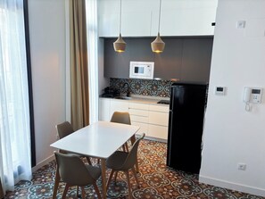 Une cuisine compacte avec un coin repas comprenant une table et des chaises, un réfrigérateur et un four à micro-ondes.