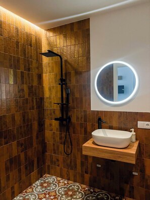 Une salle de bain avec une douche, un lavabo et un miroir.