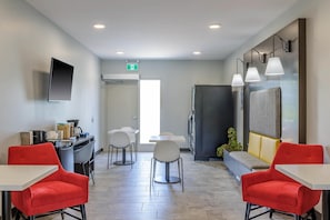 A modern hotel room with a dining area, a flat-screen TV, and a sofa. - King Room with Kitchen | Free Parking | Quick 0.5-Mile Drive to Cedar Point (Hornepayne)