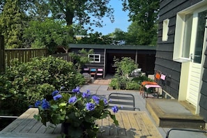 A wooden deck with a potted plant, a covered patio area, and a garage with a car inside. - SE06 Holiday home Serooskerke (Serooskerke)