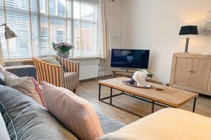 A living room with a sofa, armchair, coffee table, TV, and a cabinet. - SE06 Holiday home Serooskerke (Serooskerke)