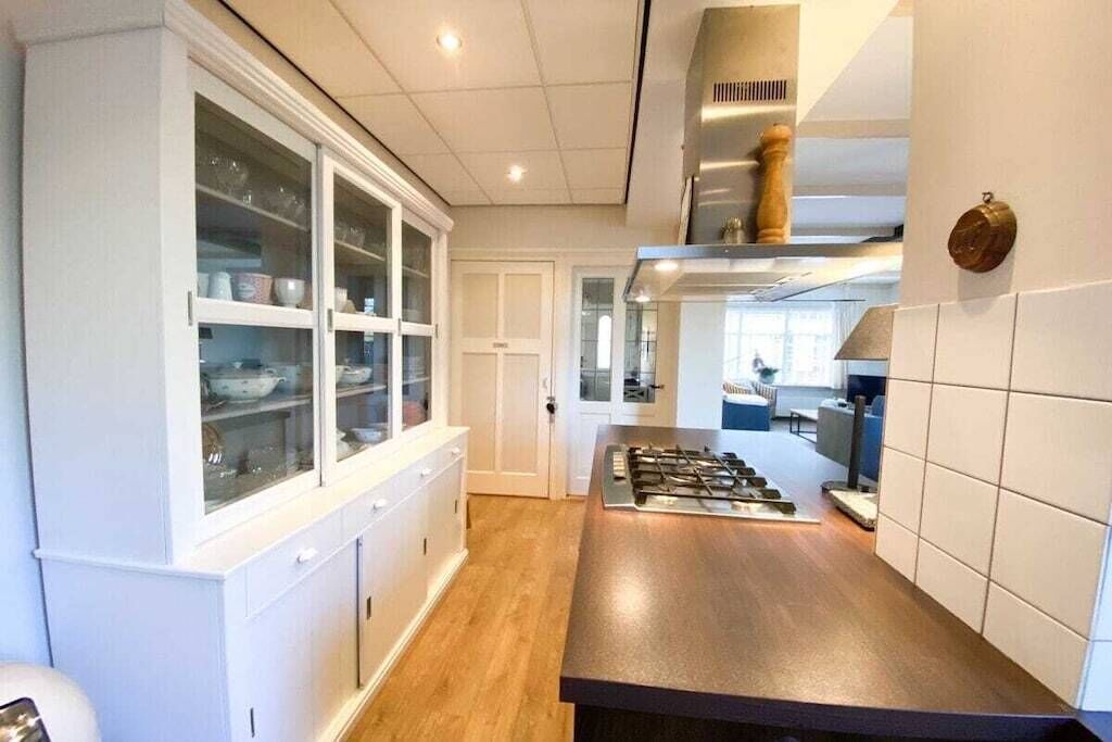 A modern kitchen with a central island, white cabinetry, and a visible stove.