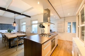 A modern kitchen with a central island, a dining area with wooden chairs, and a pendant light. - SE06 Holiday home Serooskerke (Serooskerke)