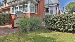 Een tweelaags huis met een bakstenen gevel, grote ramen en een overdekte veranda.