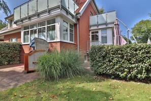 A two-story house with a brick facade, large windows, and a covered porch. - Vrbo Property (Langeoog)