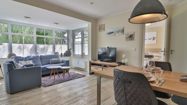 Een moderne woonkamer met een bank, salontafel en eettafel.