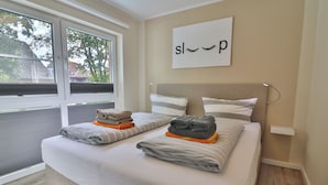 Een slaapkamer met een bed, kussens en een raam.
