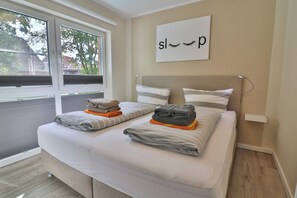 A bedroom with a bed, pillows, and a window. - Vrbo Property (Langeoog)