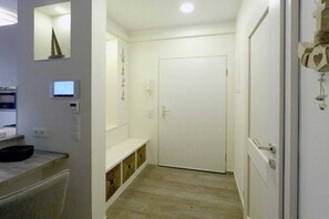 A hallway with a white door, a bench, and a small table with a bowl. - Holiday apartment with 1 bedroom (Dierhagen)
