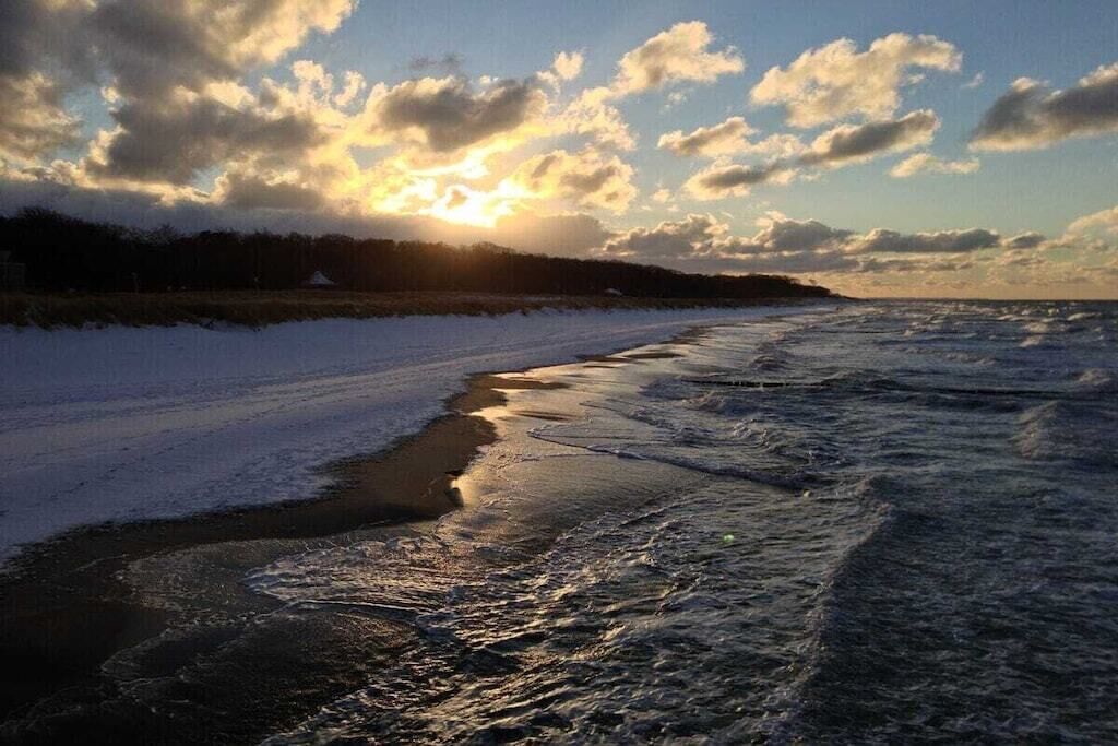 Ein Strand mit Wellen und einem Sonnenuntergang im Hintergrund.