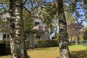 Een gebouw met een balkon, omringd door bomen en een gazon.