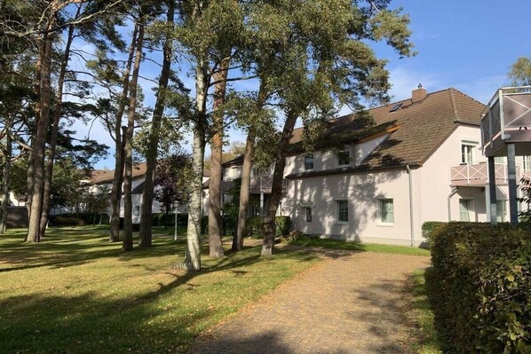 Een woonwijk met een verharde oprit die leidt naar een rij huizen, omgeven door bomen en een verzorgd gazon.