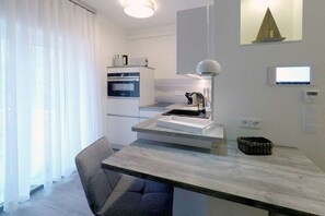 Eine moderne Küche mit Backofen, einem Esstisch mit Stuhl und einer Pendelleuchte.
