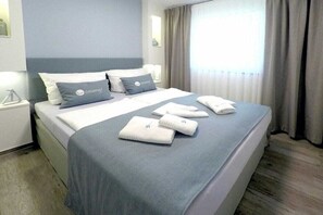 Een hotelkamer met een bed, kussens en handdoeken.