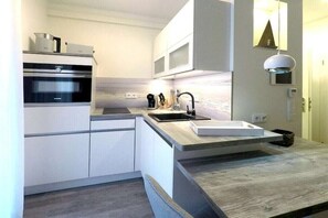 A modern kitchen with built-in appliances, a wooden countertop, and a minimalist design. - Holiday apartment with 1 bedroom (Dierhagen)