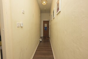A narrow hallway with a wooden floor, light switch, and a door at the end. - London Cozy Apartment Retreat (London)