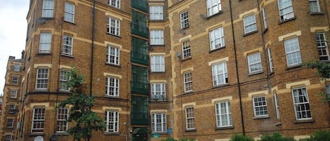 A multi-story residential building with a central entrance, brick facade, and multiple windows.