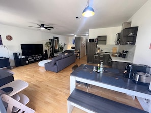 A modern living room with a grey sofa, a flat-screen TV, and a ceiling fan. - Apartment 'Zwergenwald' with Garage incl. Charging Station, Terrace, Garden & Wi-Fi (Badenweiler)