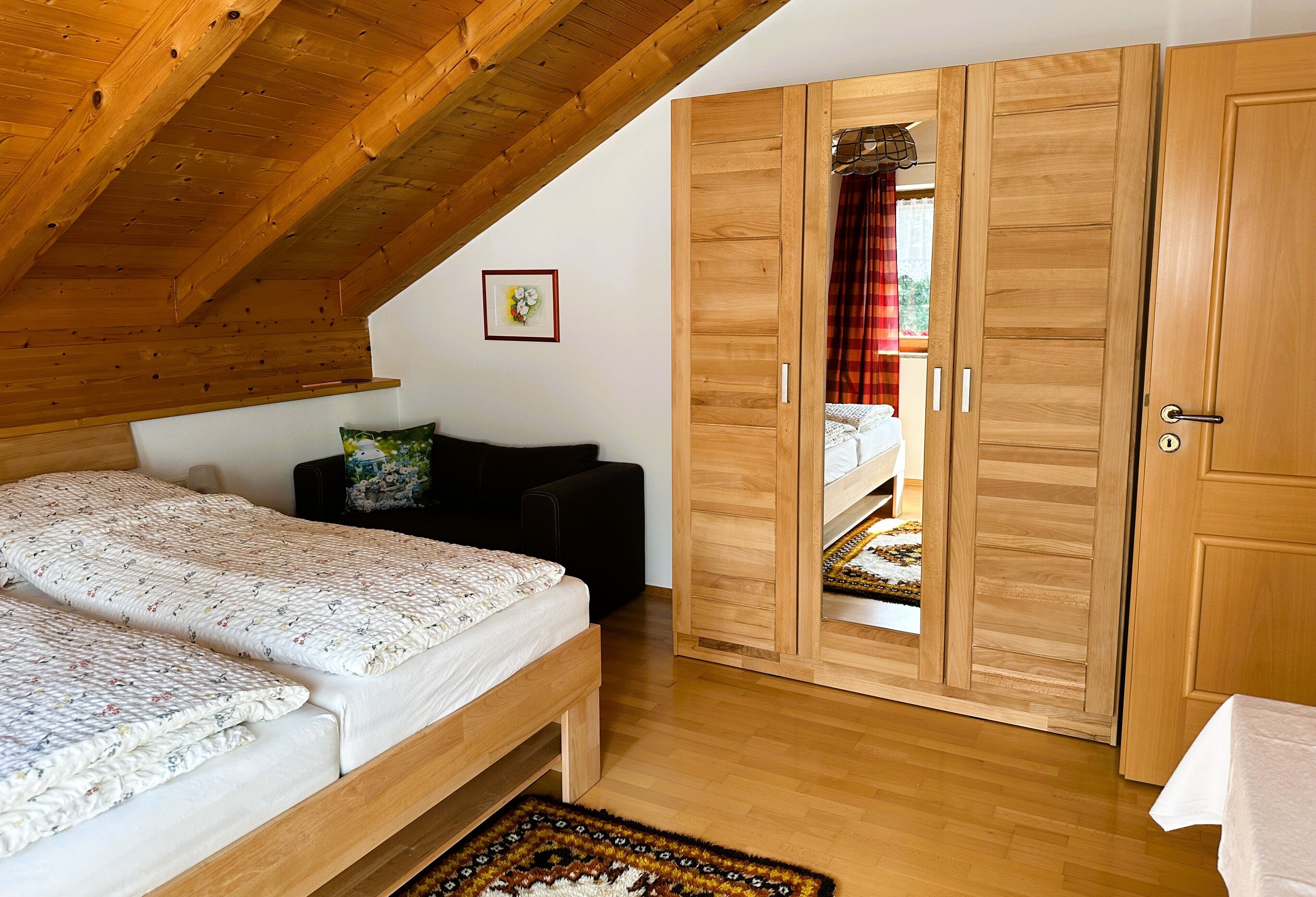 Ein Schlafzimmer mit Bett, Sofa, Kleiderschrank und Holzboden.