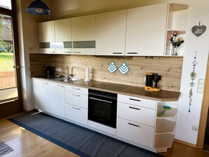 Una cocina moderna con armarios blancos, protector contra salpicaduras de madera y una cafetera.