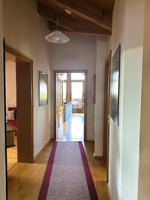 Un pasillo con techo de madera, alfombra morada y vista a una habitación con sofá y mesa.