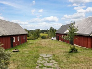 A rural property with two red barns, a paved driveway, and a car parked in the distance. - Lantdrömmen by Interhome (Hyltebruk)