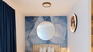 A modern bedroom with a large bed, a round mirror, and a marble wall. - Vrbo Property (Uhldingen-Mühlhofen)