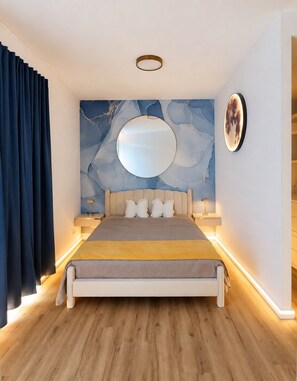 A modern bedroom with a large bed, a round mirror, and a marble wall. - Vrbo Property (Uhldingen-Mühlhofen)