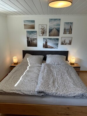 Un letto con una coperta a motivi, due lampade ai comodini e una serie di quadri appesi al muro sopra.