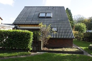 Una casa con tetto spiovente, una piccola finestra e una sezione in mattoni.