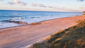 A beach with a wooden jetty, sandy shore, and a building in the distance. - OK24 Holiday home with dog Oostkapelle (Oostkapelle)