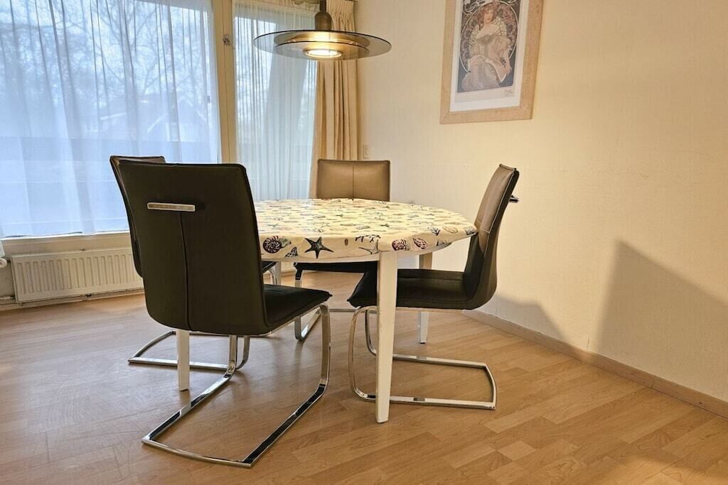 A dining area with a round table, four chairs, and a pendant light.