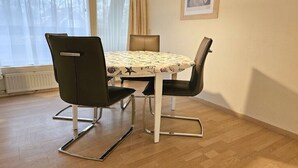 A dining area with a round table, four chairs, and a pendant light. - OK24 Holiday home with dog Oostkapelle (Oostkapelle)