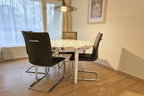 Ein Essbereich mit einem runden Tisch, vier Stühlen und einer Pendelleuchte.