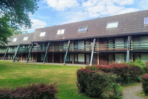 Eine Reihe moderner, mehrstöckiger Gebäude mit Balkonen, einem grünen Innenhof und blauem Himmel.
