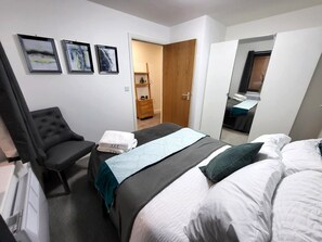 A hotel room with a bed, a chair, a desk, and a wardrobe. There are three framed pictures on the wall. - Inclusive 1BR Central Abode w Parking and Balcony (Liverpool)